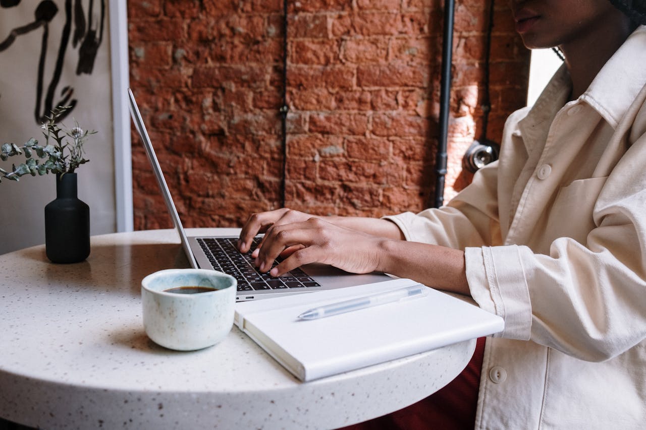 services-04 Woman working on a laptop with coffee in a cozy café, highlighting a productive and modern vibe.